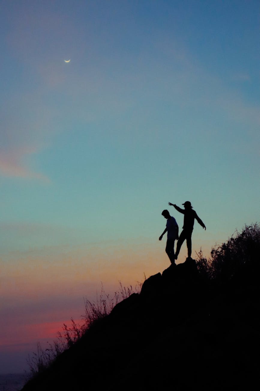 silhouette of a two people standing on rock