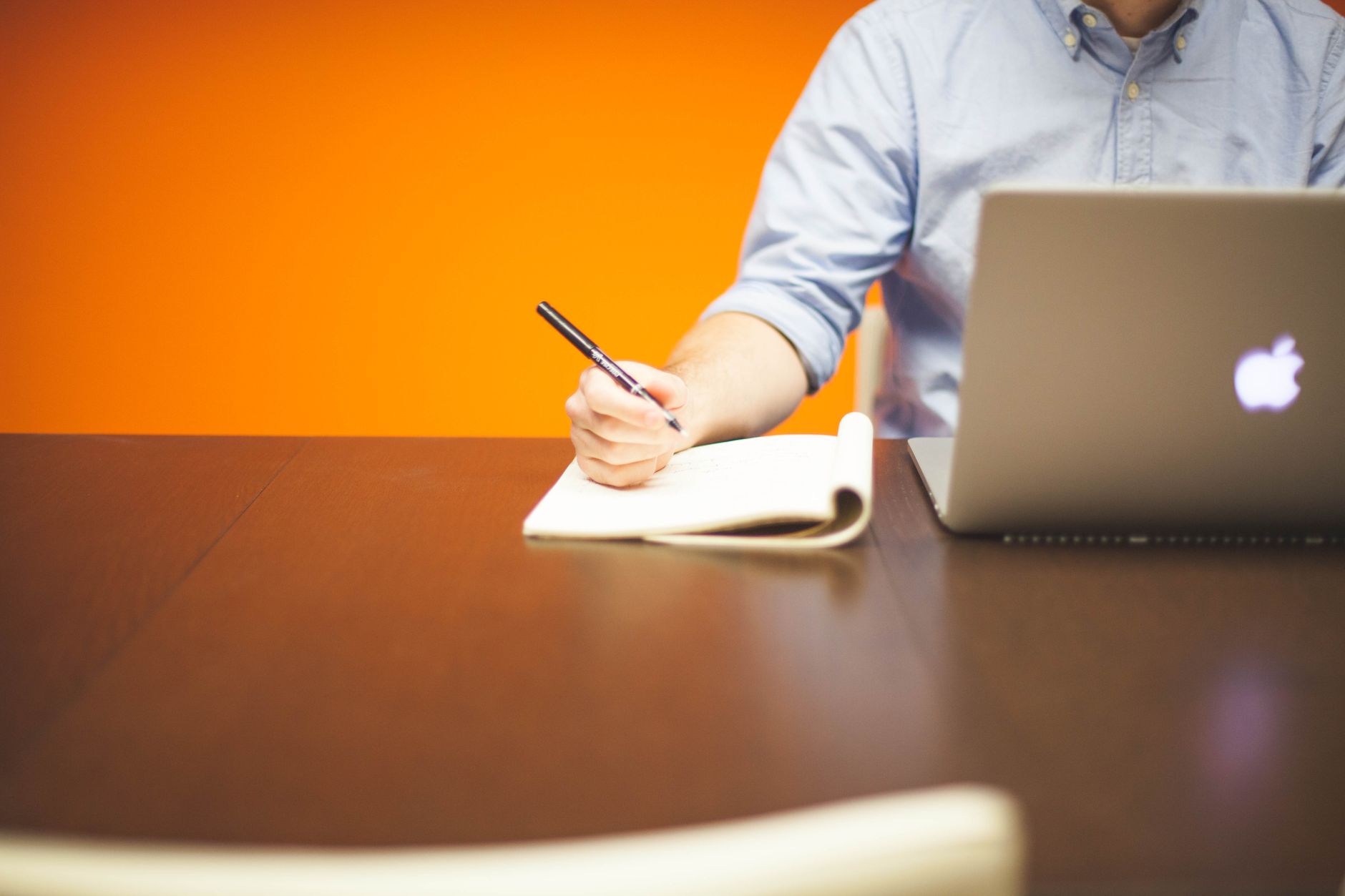 man using macbook while holding pen